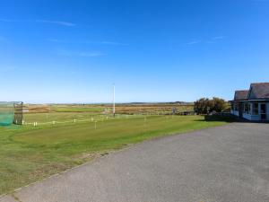 a baseball field with a fence and a building at Tides Reach in Rhosneigr
