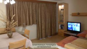 Un dormitorio con una cama y un televisor en una habitación. en Haus Obermoser, en Kitzbühel