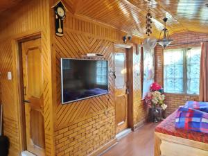 a living room with a television on a wall at Mehdudia Guest House in Shimla