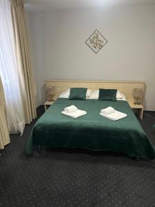 a bedroom with a green bed with two towels on it at Hotel Pacific in Timişoara