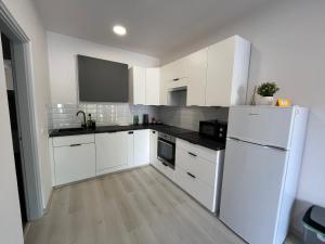 a kitchen with white cabinets and a white refrigerator at Házikon 1 in Nyíregyháza