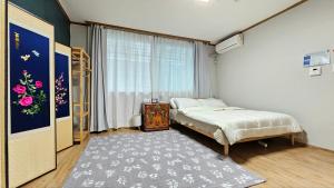 1 dormitorio con cama, ventana y alfombra en Byulchae Guest House - Foreigner Only, en Seúl