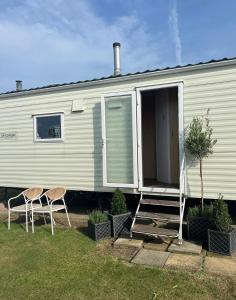 a mobile home with two chairs and a porch at Ecco Lodge Caravan in Leysdown-on-Sea