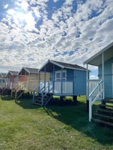 a row of colourful beach huts on the grass at Ecco Lodge Caravan in Leysdown-on-Sea