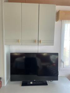 a television in a kitchen with white cabinets at Ecco Lodge Caravan in Leysdown-on-Sea