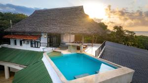 a villa with a swimming pool and a thatched roof at Shimoni Reef Lodge in Shimoni