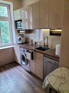 a kitchen with a sink and a washing machine at Apartament 90m2, do 8 osób, salon, 3 sypialnie in Koszalin