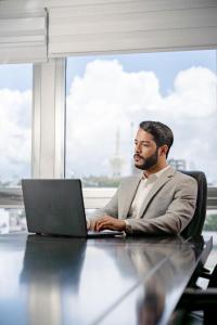 a man sitting at a table with a laptop computer at Hodelpa Centro Plaza in Santiago de los Caballeros