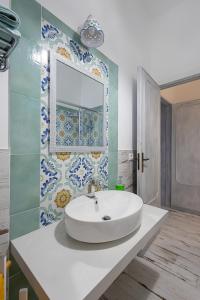 un bagno con un lavandino bianco e uno specchio di Di Mari e d'Amuri Casa Vacanza a Tonnara di Bonagia