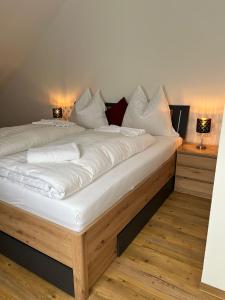 a large bed with white sheets and pillows on it at Apartments und Zimmervermietung in Liesingthal