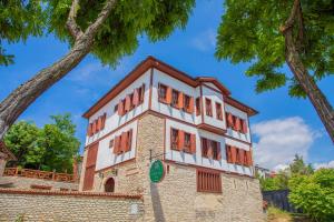 a building with orange shuttered windows and a tree at Saffronia1900 Butik Otel in Safranbolu