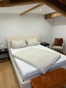a bedroom with a white bed and a chair at Erholungsloft in Bad Buchau