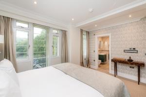 a white bedroom with a bed and a bathroom at Fountain House Apartments - London in London