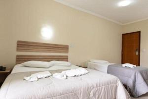 a bedroom with two beds with towels on them at Colonial Flat Hotel in Itapetininga