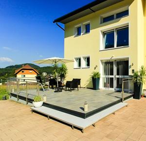 ein Haus mit einer großen Terrasse davor in der Unterkunft Komfortappartements Schönblick in Sankt Kanzian am Klopeiner See