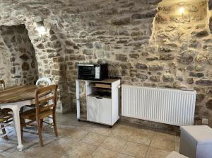 a kitchen with a table and a microwave at Gites du Mas Bouscas in Saint-Florent-sur-Auzonnet