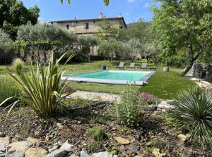 a pool in a garden with a house in the background at Gites du Mas Bouscas in Saint-Florent-sur-Auzonnet
