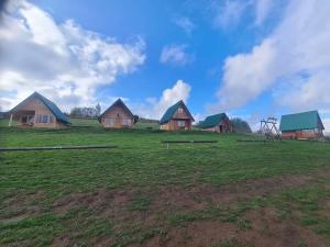 a group of wooden houses in a field with a sky at Markove kolibe 5, Uvac, Sjenica in Sjenica