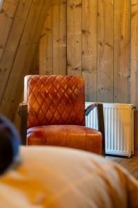 ein orangefarbener Stuhl in einem Raum mit Holzwänden in der Unterkunft De oude walnoot in Sint Pancras