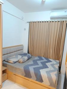 a small bedroom with a bed with a curtain at Apartemen Sky House BSD in Cilenggang