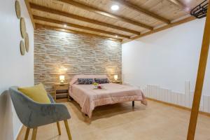 a bedroom with a bed and a chair and a brick wall at Apartamento Vemar in La Guancha