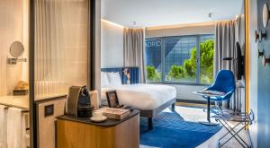 a hotel room with a bed and a blue chair at Pullman Madrid Airport & Feria in Madrid +52 photos