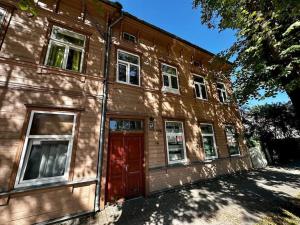 an old wooden building with a red door at 2nd floor Casa Kungu Street in Liepāja