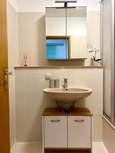 une salle de bain avec un lavabo et un miroir dans l'établissement Sabine´s Ferienwohnung mit Bergblick am Chiemsee, à Prien am Chiemsee