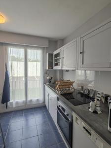 kuchnia z białymi szafkami i dużym oknem w obiekcie Appartement 3 pièces cœur ville w mieście Quiberon