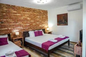 two beds in a room with a brick wall at Maksimilijan Winery Apartments & wine tasting in Pepelište