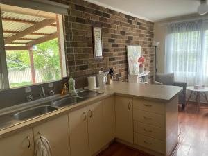 eine Küche mit zwei Spülbecken und einer Ziegelwand in der Unterkunft Canberra Hospital Locum Welcome- 2BR Home in Harman + 42 Fotos