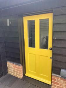 een gele deur aan de zijkant van een gebouw bij Wood Lodge in Bungay +7 foto's