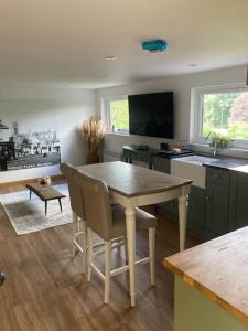 a kitchen with a table and chairs and a television at Wood Lodge in Bungay