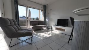 a living room with a couch and a tv at FLEUR De LYS - PROCHE CENTRE VILLE ET LAC in Thonon-les-Bains