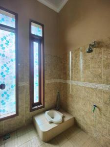 a bathroom with a toilet and a window at Padi Loka Villa Kuningan in Koreak
