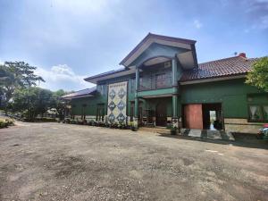 a green building with a balcony and a driveway at Padi Loka Villa Kuningan in Koreak