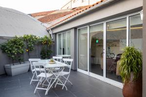 a patio with white chairs and a table and windows at Hotel Rali Viana in Viana do Castelo