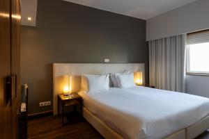 a bedroom with a large white bed with two lamps at Hotel Rali Viana in Viana do Castelo