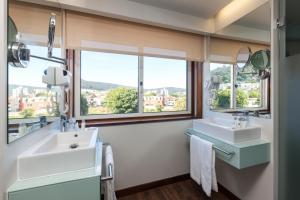 a bathroom with two sinks and two windows at Hotel Rali Viana in Viana do Castelo