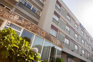 a building with glass windows and a tree at Hotel Rali Viana in Viana do Castelo