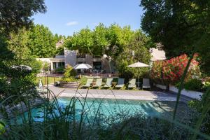 a pool with chairs and umbrellas in a yard at Hôtel 96 in Marseille