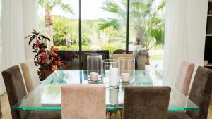 a glass dining room table with chairs and a window at Villa luxeuse et climatisee sur le golf, piscine chauffee in Essaouira