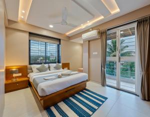 コールハープルにあるOrchid Avenueの大きなベッドと大きな窓のある寝室