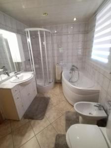 a bathroom with a tub and a toilet and a sink at maison de vacances chez louis in Sondernach