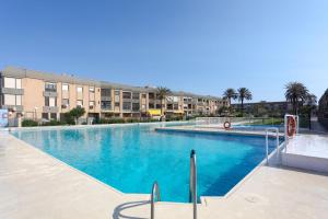 a large swimming pool with palm trees and buildings at BAJO primera línea playa, Retamar, Cabo de Gata in Retamar