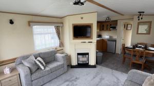 a living room with a couch and a fireplace at Coastal Caravan in Solva in Haverfordwest +27 photos