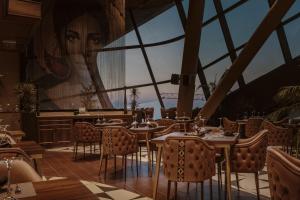 a restaurant with tables and chairs and a large window at Chic & Cheeky Reside in Malta's Tallest Skyscraper in St Julian's