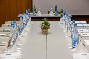a long table with white tables with bottles and a plant on it at Hotel Rali Viana in Viana do Castelo
