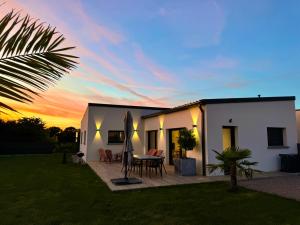 a house with a patio with a table and a surfboard at Maison neuve 4 étoiles plain-pied proche de la mer in Plurien
