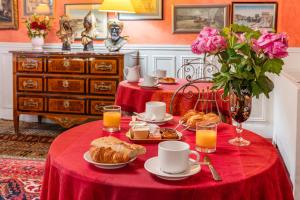 ein Tisch mit einer roten Tischdecke und Frühstücksspeisen darauf in der Unterkunft Hôtel De Nice in Paris